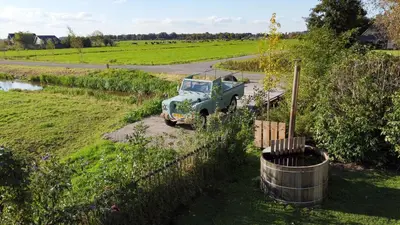an old truck parked in a field next to a fence at De Lindenhof in Tienhoven
