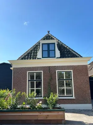 a red brick house with a gambrel roof at Rhynhoven Lodge in Hazerswoude-Rijndijk