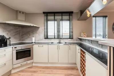 a kitchen with white cabinets and stainless steel appliances at Spacious 120m2 Water Villa With Sauna Near Amsterdam in Aalsmeer