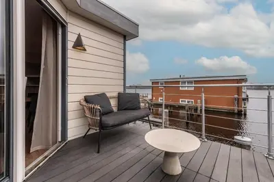 a balcony with a chair and a table on a building at Spacious 120m2 Water Villa With Sauna Near Amsterdam in Aalsmeer