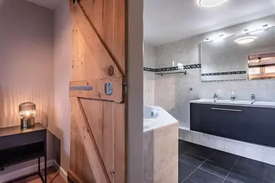 a bathroom with a wooden door and a sink and a tub at Spacious 120m2 Water Villa With Sauna Near Amsterdam in Aalsmeer