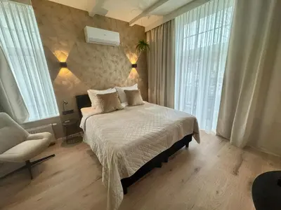 a bedroom with a bed and a chair and windows at Seastreet Suite in Zandvoort