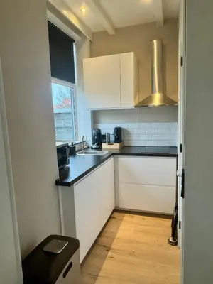 a small kitchen with white cabinets and a sink at Seastreet Suite in Zandvoort