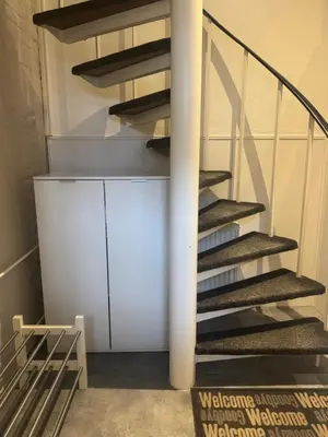 a spiral staircase in a room with a white cabinet at Seastreet Suite in Zandvoort