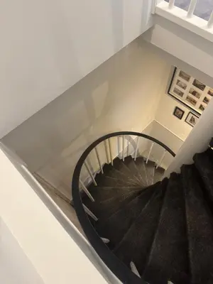 a black spiral staircase in a white room at Seastreet Suite in Zandvoort