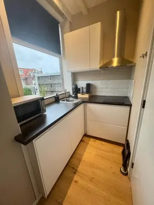 a small kitchen with a sink and a window at Seastreet Suite in Zandvoort