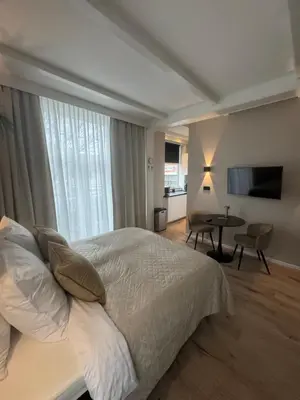 a bedroom with a bed and a table and a television at Seastreet Suite in Zandvoort