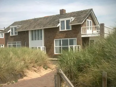 a house on top of a beach with grass at Pacific Ocean View Comfortable Holiday Residence in Bergen aan Zee