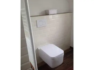 a white toilet in a bathroom with a white tile wall at Pacific Ocean View Comfortable Holiday Residence in Bergen aan Zee