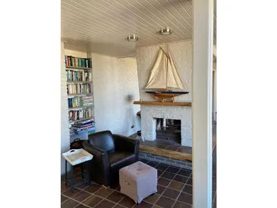 a living room with a chair and a fireplace at Pacific Ocean View Comfortable Holiday Residence in Bergen aan Zee