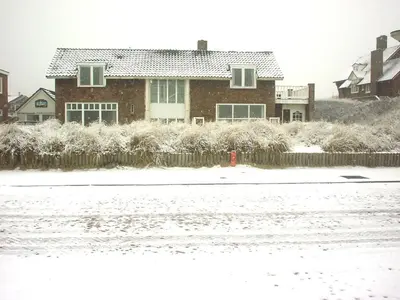 a house with a fence in the snow at Pacific Ocean View Comfortable Holiday Residence in Bergen aan Zee