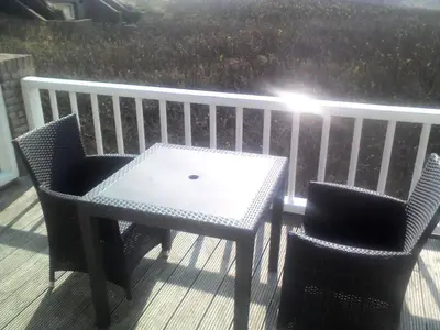 a table and two chairs sitting on a deck at Pacific Ocean View Comfortable Holiday Residence in Bergen aan Zee
