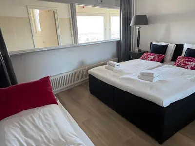 a bedroom with two beds and a large window at Rosalie Apartment in Zandvoort