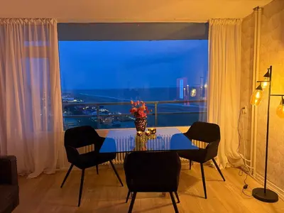 a dining room with a table and a large window at Rosalie Apartment in Zandvoort