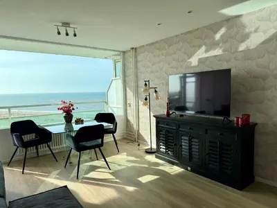 a living room with a television and a table and chairs at Rosalie Apartment in Zandvoort