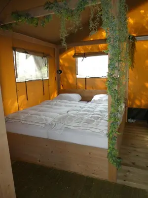 a large bed in a room with two windows at Zorgcamping De Ruif De Peppelhoeve in Stoutenburg