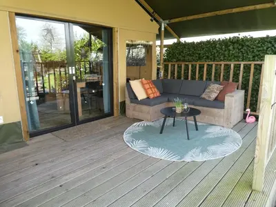 a patio with a couch and a table on a deck at Zorgcamping De Ruif De Peppelhoeve in Stoutenburg