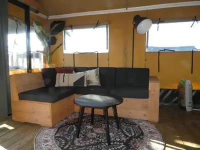 a living room with a couch and a stool at Zorgcamping De Ruif De Peppelhoeve in Stoutenburg