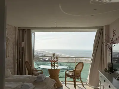 a bedroom with a table and a view of the ocean at Studio Michelle in Zandvoort