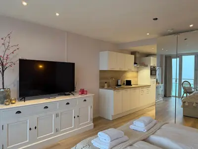 a large white kitchen with a flat screen tv at Studio Michelle in Zandvoort