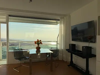 a living room with a table and a large window at Piano Apartment in Zandvoort