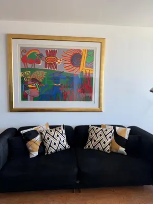 a black couch in a living room with a painting at Piano Apartment in Zandvoort