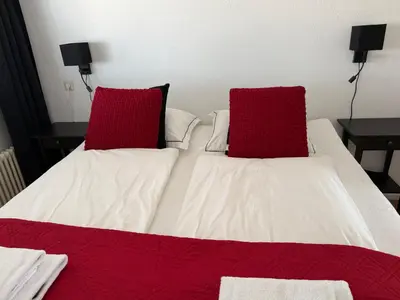 a bed with two red pillows on top of it at Piano Apartment in Zandvoort