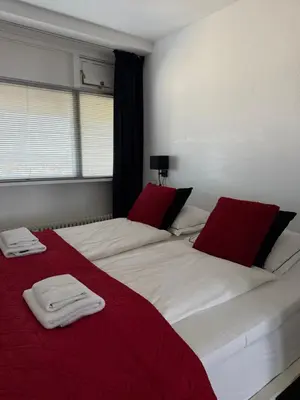 a bedroom with two beds with red and white sheets at Piano Apartment in Zandvoort