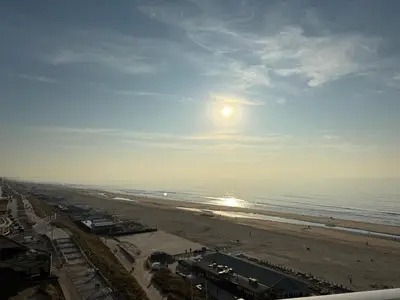 a view of a beach with the sun in the sky at Piano Apartment in Zandvoort