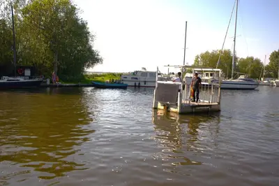 two people standing on a boat in the water at Glampingtent de Deiling, de Woudhaven in De Woude
