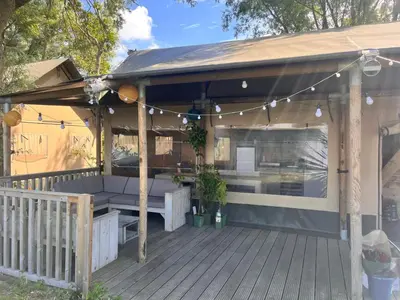 a pergola with a bench and a table on a deck at Glampingtent de Deiling, de Woudhaven in De Woude