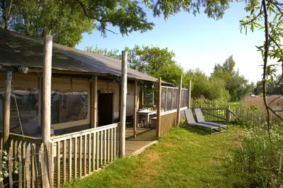 a house with a porch with a table and chairs at Glampingtent de Deiling, de Woudhaven in De Woude
