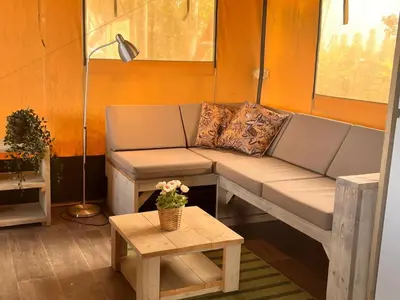 a living room with a couch and a table at Glampingtent de Deiling, de Woudhaven in De Woude