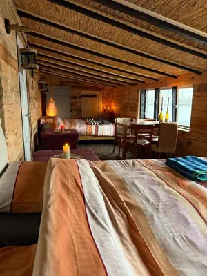 a bedroom with two beds and a table in a room at The Historical Trick Hut in the middle of the Lake in Baambrugse Zuwe