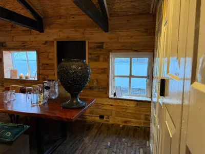 a wooden room with a table with a vase on it at The Historical Trick Hut in the middle of the Lake in Baambrugse Zuwe