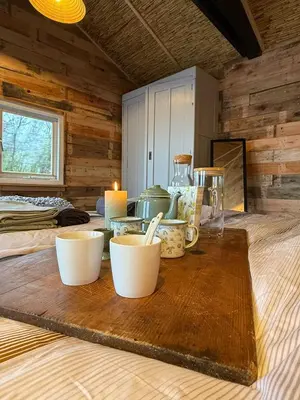 a table with cups and candles on a wooden table at The Historical Trick Hut in the middle of the Lake in Baambrugse Zuwe
