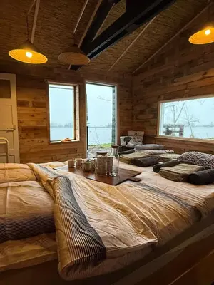 a large bed in a room with wooden walls at The Historical Trick Hut in the middle of the Lake in Baambrugse Zuwe