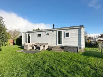 a white tiny house in a grassy yard at Chalet 7a op Recreatiepark De Wielen in Sint Maarten