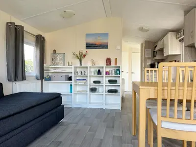 a living room with a table and a dining room at Chalet 7a op Recreatiepark De Wielen in Sint Maarten