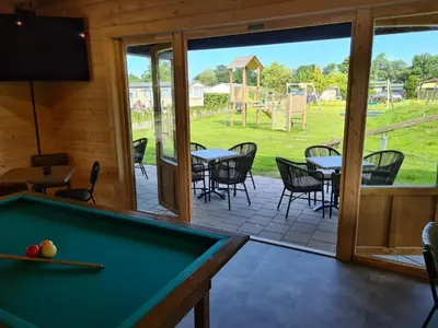 a room with a pool table and a patio at Chalet 7a op Recreatiepark De Wielen in Sint Maarten