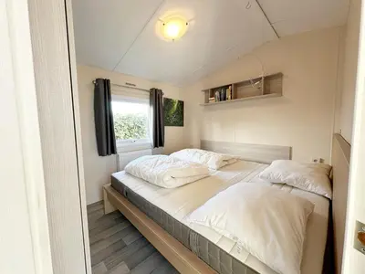 a bedroom with two beds and a window at Chalet 7a op Recreatiepark De Wielen in Sint Maarten