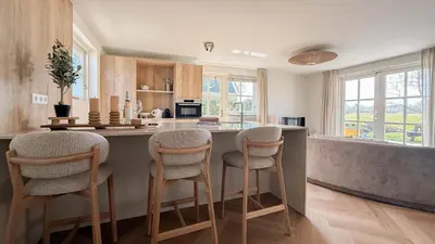 a kitchen with a bar with stools at a counter at Zon aan den Hoef by Droomvilla in Egmond aan den Hoef