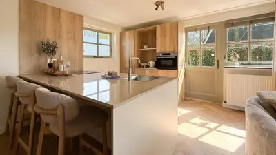 a kitchen with a counter and some chairs in it at Zon aan den Hoef by Droomvilla in Egmond aan den Hoef