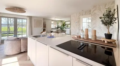 a large kitchen with white cabinets and a counter top at Zon aan den Hoef by Droomvilla in Egmond aan den Hoef
