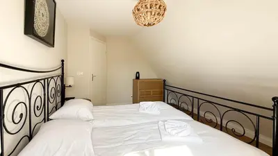 a bedroom with two beds with white sheets and a chandelier at Zon aan den Hoef by Droomvilla in Egmond aan den Hoef