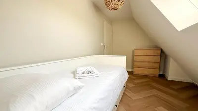 a white bedroom with a bed and a dresser at Zon aan den Hoef by Droomvilla in Egmond aan den Hoef
