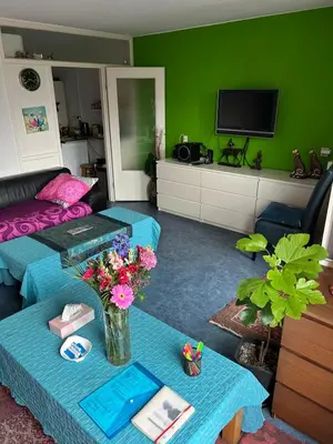 a living room with a couch and a table with flowers at B&B Calypso Amsterdam in Amsterdam