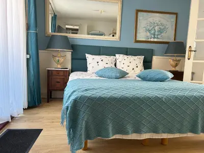 a bedroom with a bed with a green comforter and a mirror at Leoicom in Zandvoort
