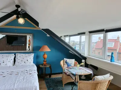 a bedroom with a bed and a table and some windows at Leoicom in Zandvoort