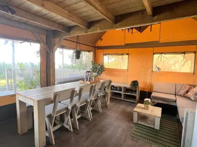 a dining room with a long table and chairs at Glampingtent de Saskerlei, de Woudhaven in De Woude